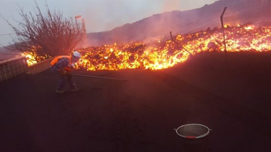 An image of a person sampling an active lava flow with a trident in the rain.