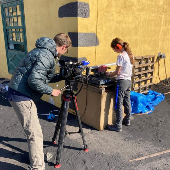 An image of Olivia Barbee cutting rock samples whilst being filmed and interviewed by Agence France-Presse.